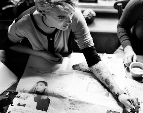 A journalist working through printed newspapers