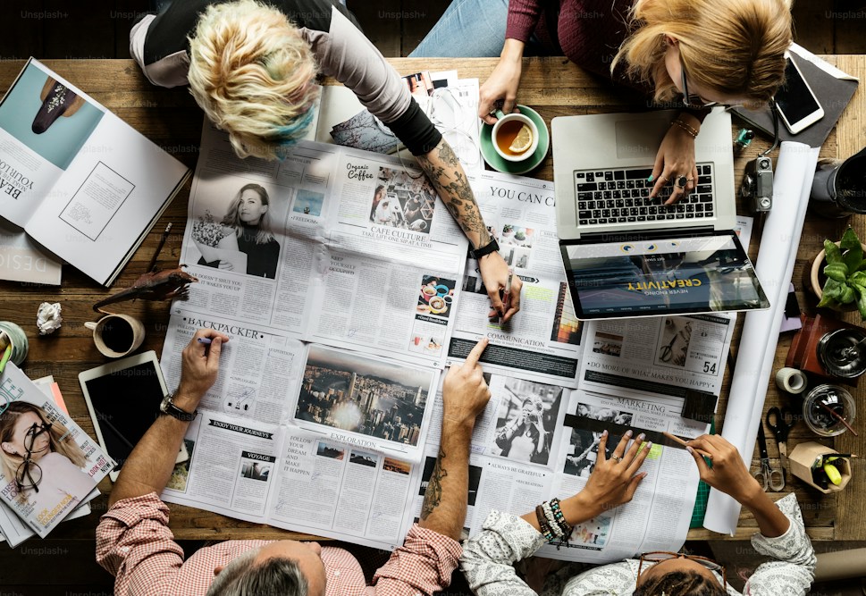 A team reviewing printed newspapers and press coverage around a table